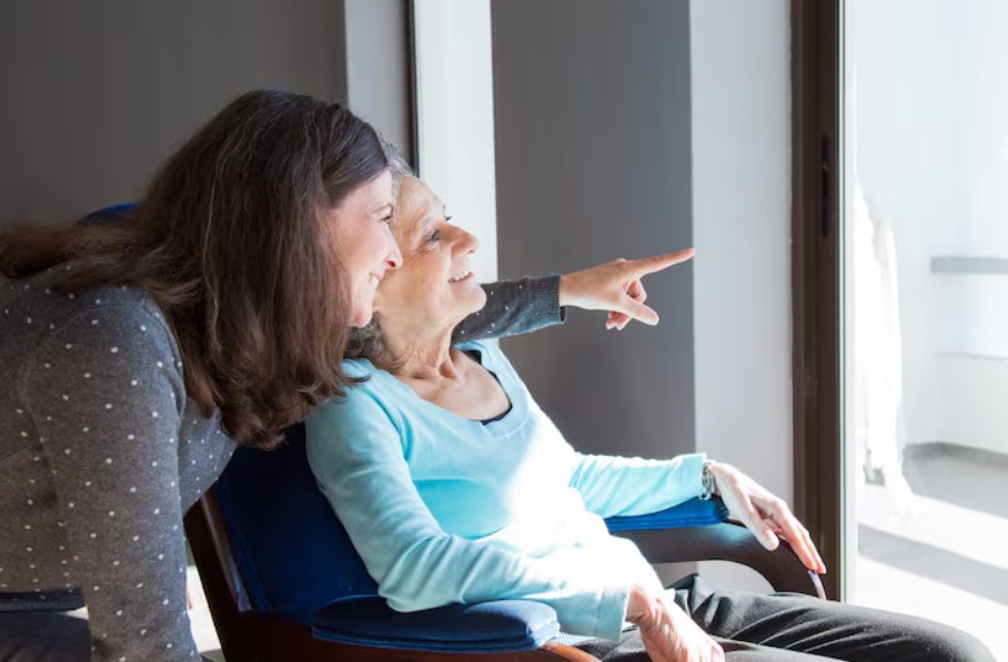 Cuidadora mirant per la finestra i fent companyia a una persona gran 