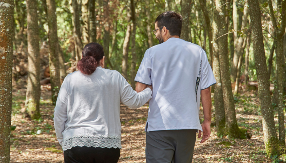 Fisioterapeuta de la residència passejant amb una persona atesa