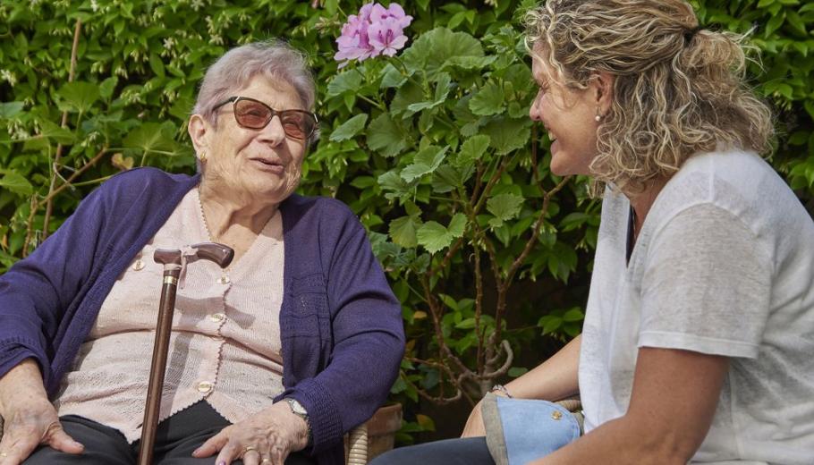Directora de la residència Colonia Guell parlant amb una persona atesa al pati