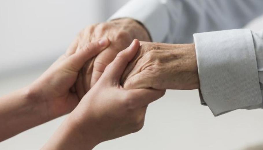 Enfermera sostenint mans de persona gran