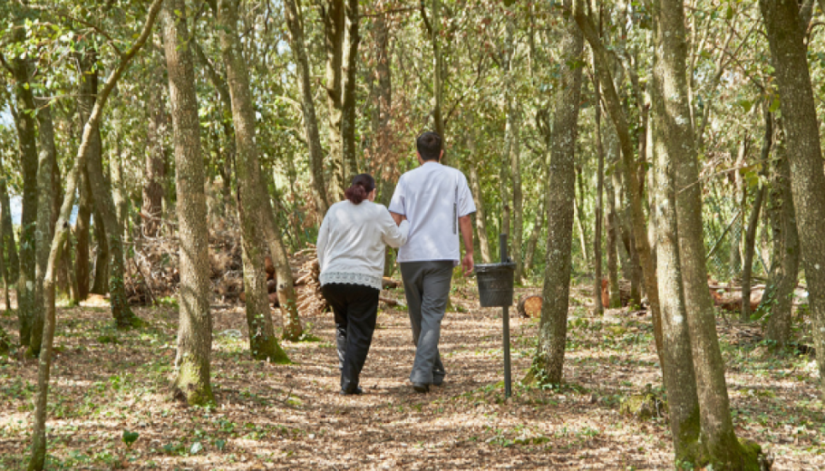Cuidador i persona gran passejant pel bosc