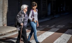 mujer acompañando a persona mayor a cruzar la calle 
