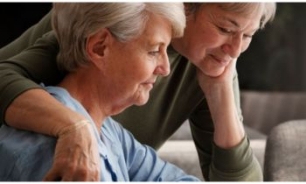 Mujer mayor mirando pantalla junto a su hija 