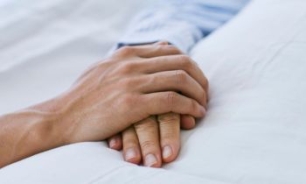 Mano sujetando otra mano en cama 