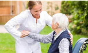 enfermera ayudando a levantarse a una mujer mayor 