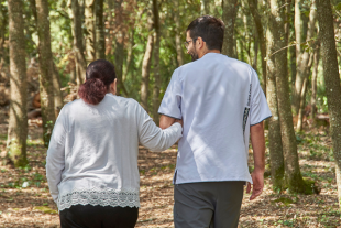 Fisioterapeuta de la residència passejant amb una persona atesa