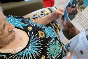 Persona gran llegint la revista Famileo a la residència Colònia Güell