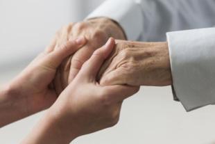 Enfermera sostenint mans de persona gran